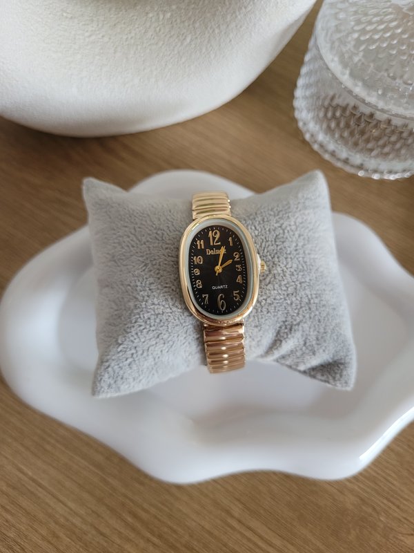 Reloj dorado con esfera negra ovalada